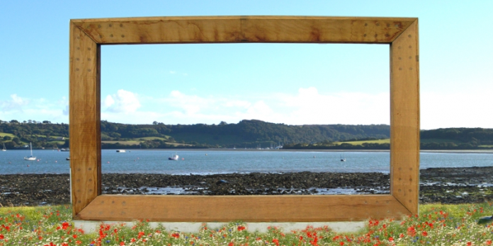 torpoint-rame-peninsula-vision-economic-plan-clifton-emery-design A large wooden frame surrounded by grass and flowers, overlooking boats in a bay